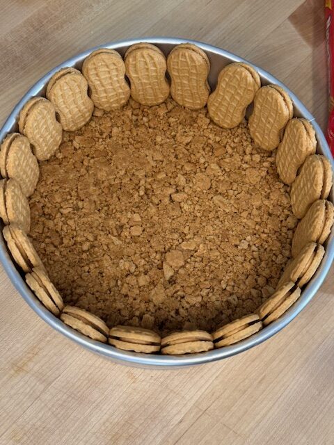 Line the edge of the pan with nutter butter cookies standing upright.
