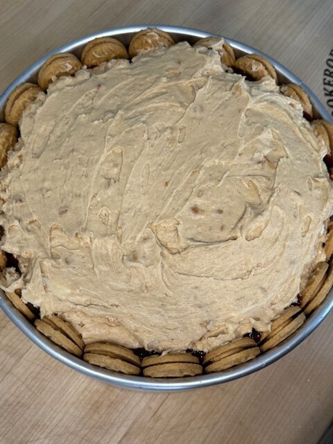 Finished no-bake peanut butter and jelly cheesecake in a metal pan on top of a wooden cutting board.