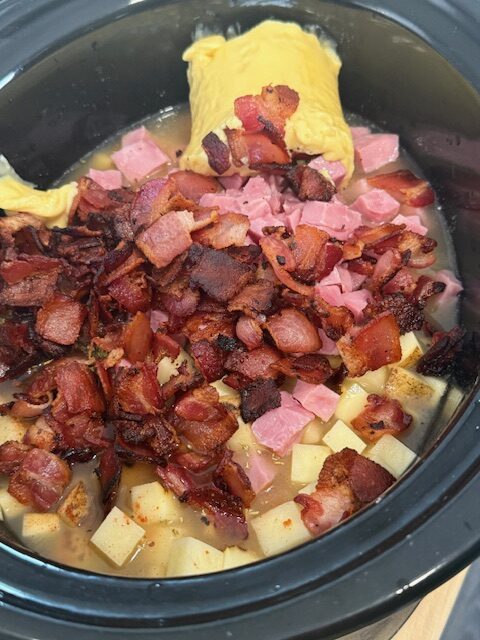 Add the ham and the bacon to the soup in the crockpot bowl.