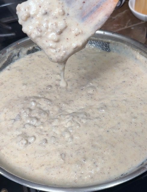 Spoon showing thickness of gravy over pan once finished cooking.