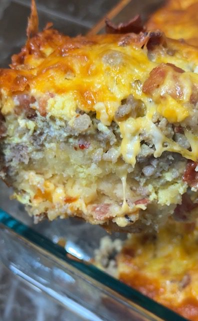 A slice of ultimate breakfast casserole showing all the layers of egg, cheese, sausage, and biscuit.