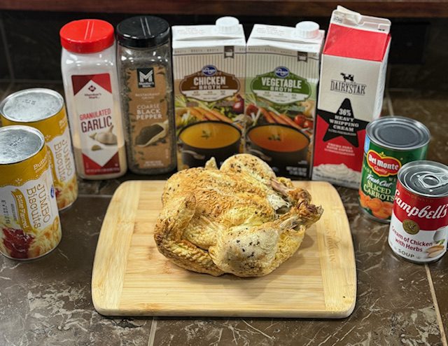 Ingredients displayed on the kitchen counter for easy chicken and dumplings. Ingredients include rotisserie chicken, canned biscuits, vegetable stock, chicken stock, heavy cream, cream of chicken soup, garlic powder, sliced carrots. 