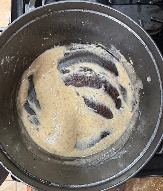 Flour is added to the bacon fat in the pot and stirred to make a roux. 