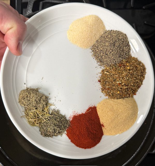 Spices on a white plate are ready to be added to the pot. 