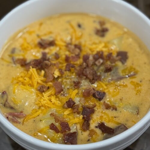 Finished cheesy potato soup in a white bowl.