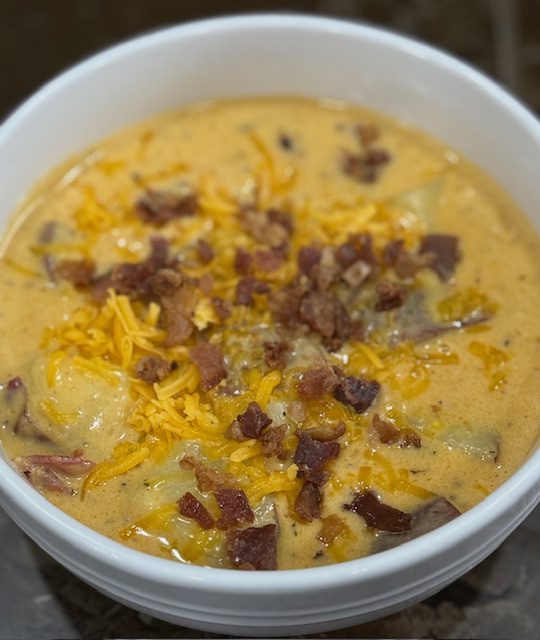 Finished cheesy potato soup in a white bowl. 