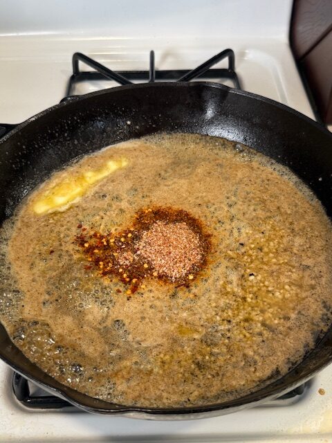 Butter has been added to the cast iron skillet on the stovetop with the garlic, salt, black pepper, and smoked paprika.