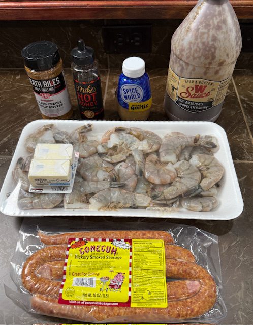 Ingredients for shrimp and sausage bites. They include raw shrimp, smoked sausage, butter, creole seasoning, hot honey, garlic, and Worcestershire sauce.