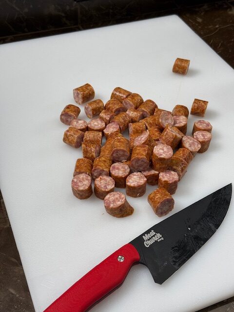 Sliced smoked sausage on a cutting board with a chef's knife.