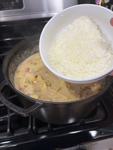 Grated romano cheese and heavy cream are added to creamy chicken noodles in the Dutch oven last to simmer before enjoying. 