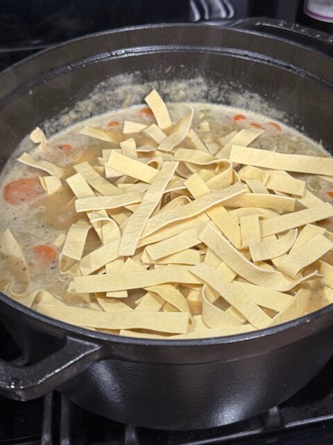 Egg noodles are added to the Dutch oven for creamy chicken noodles. 