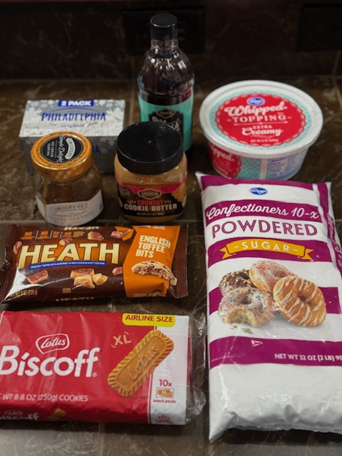 Ingredient for Biscoff cookie dip. Ingredients include cream cheese, caramel sauce, whipped topping, powdered sugar, biscoff cookies, Heath toffee bits, and vanilla extract. 