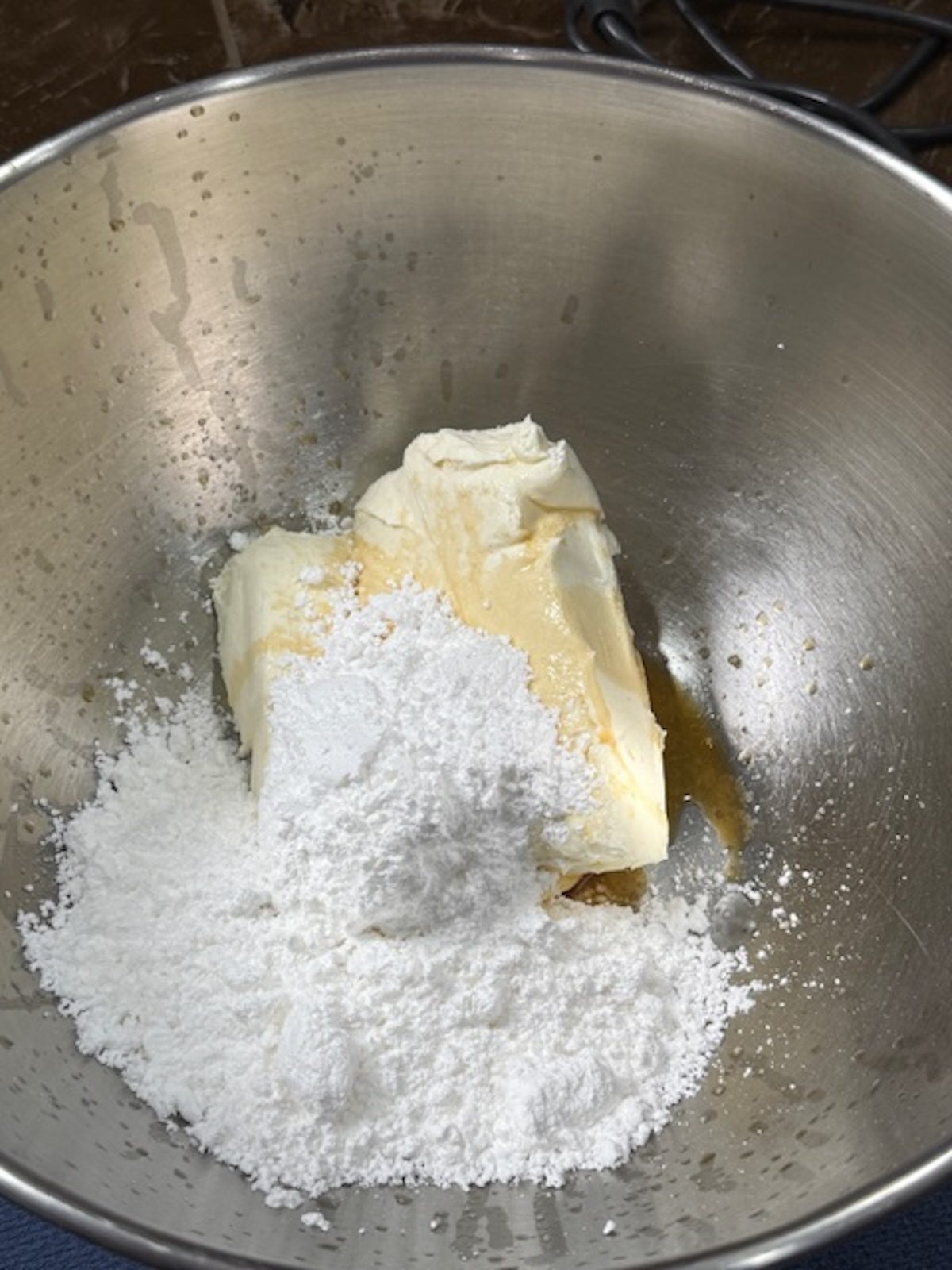 Cream cheese and powdered sugar in a mixing bowl with vanilla.
