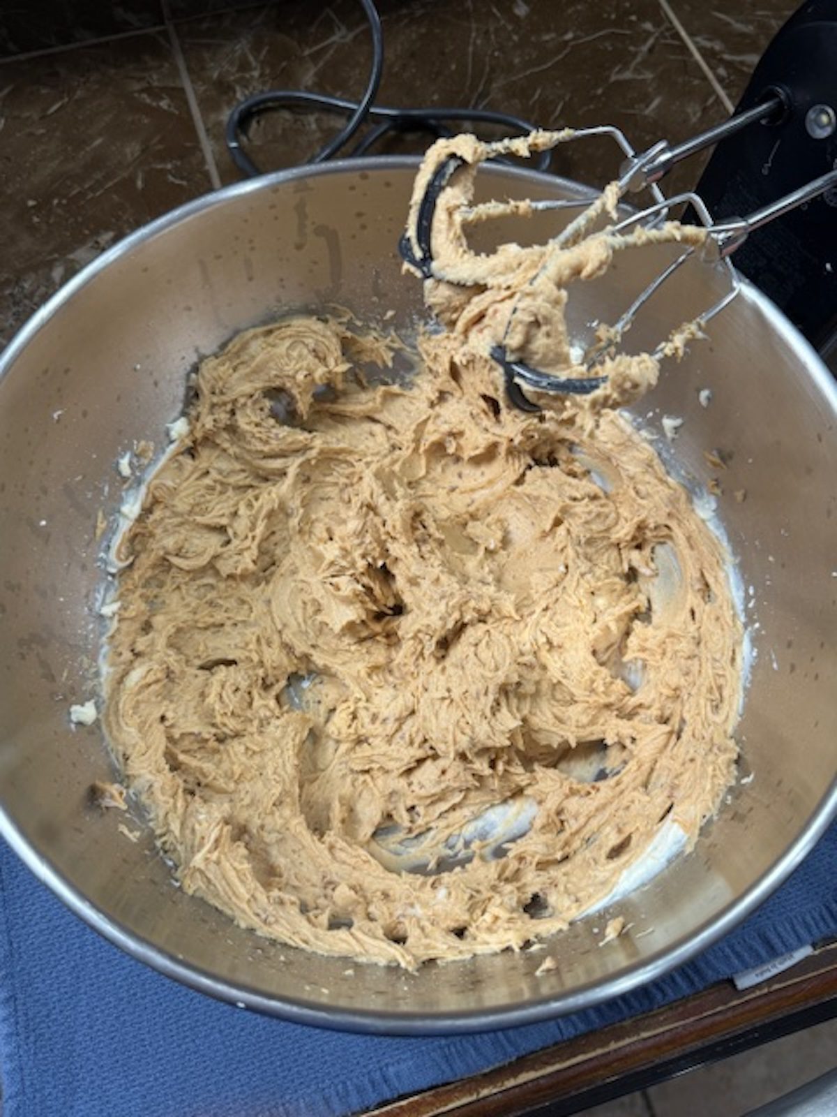 A hand mixer is beating the cream cheese, powdered sugar and vanilla mixture.