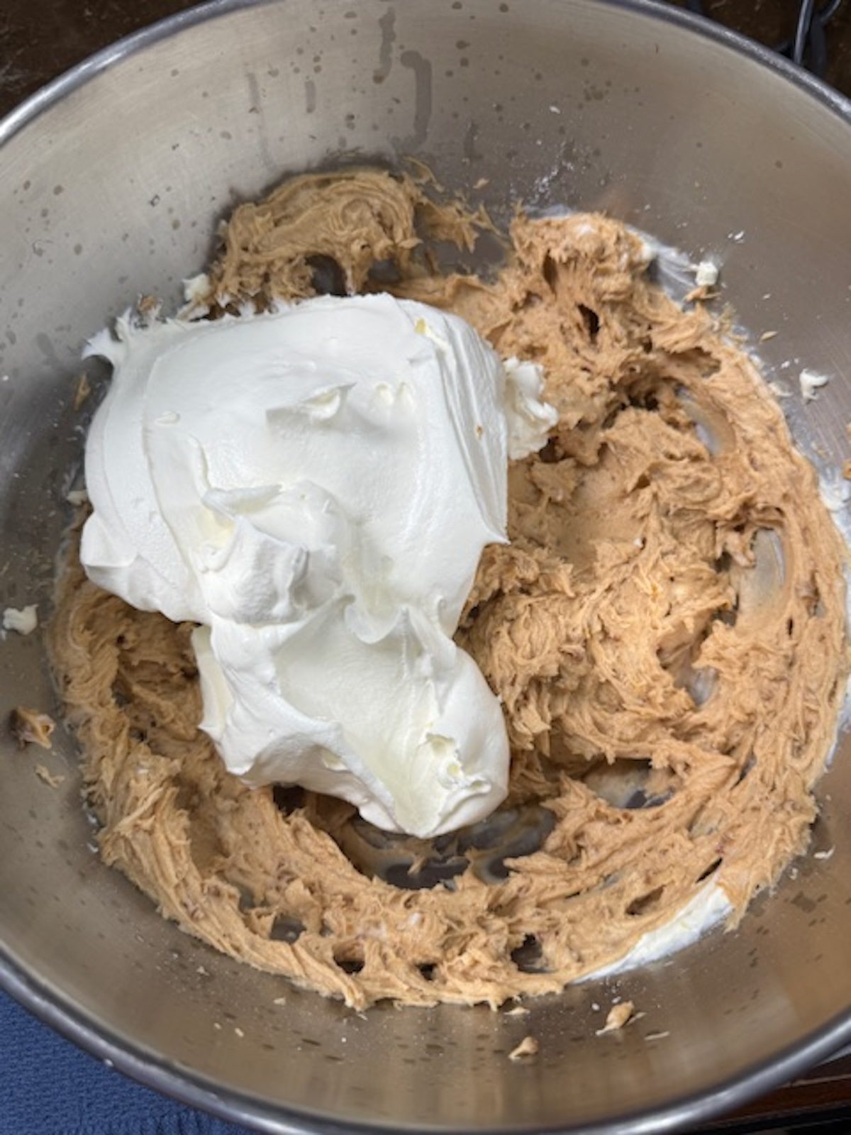 Adding the whipped cream into the Biscoff cookie dip in a metal bowl.
