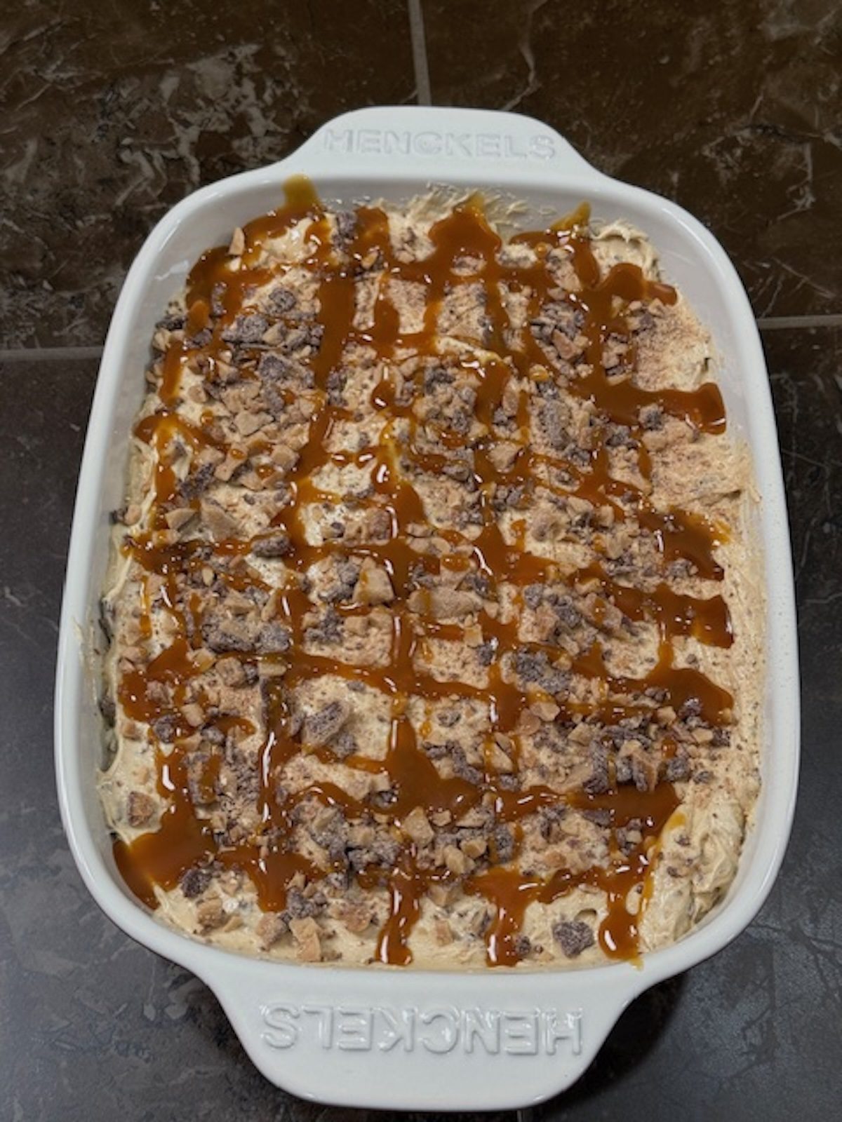 Finished biscoff cookie dip with caramel sauce, cookies, and chocolate on top.