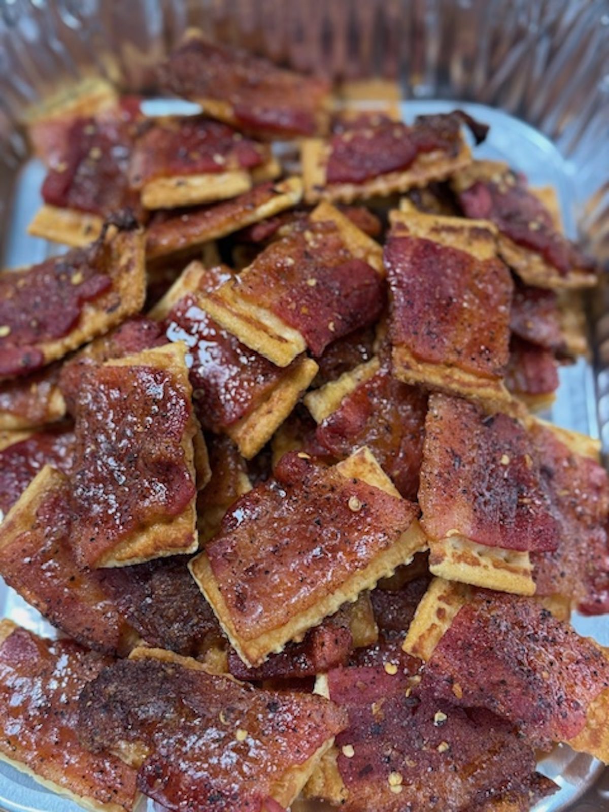 Finished bacon crackers are piled in a foil tin.