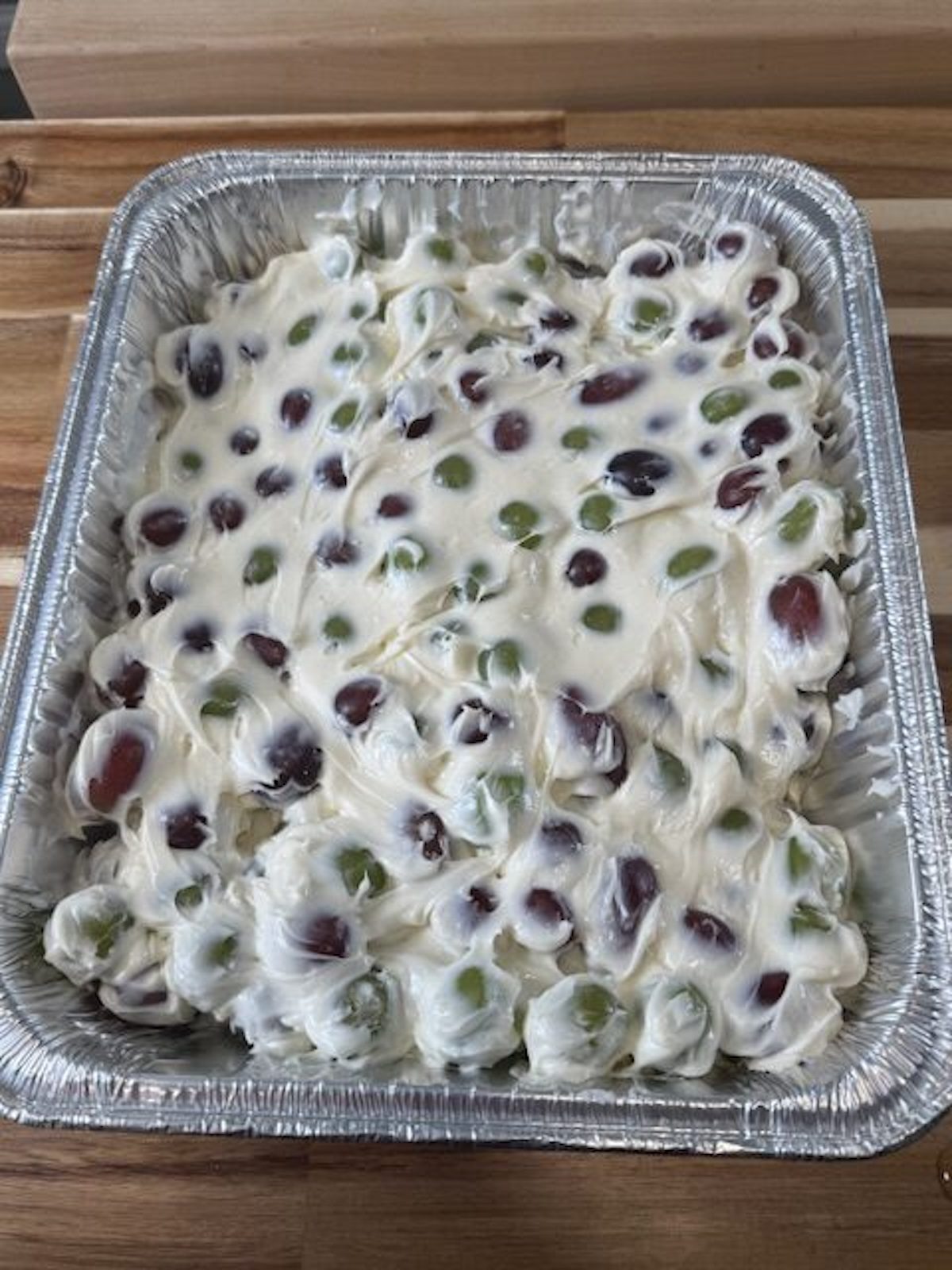 Creamy grape salad mixture is spread in a foil pan.