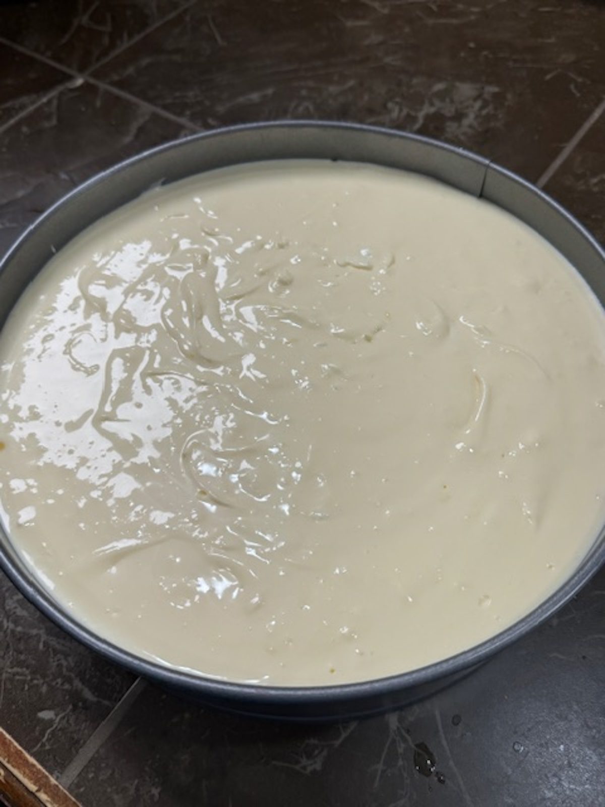 A springform pan has the lemon cheesecake batter inside.