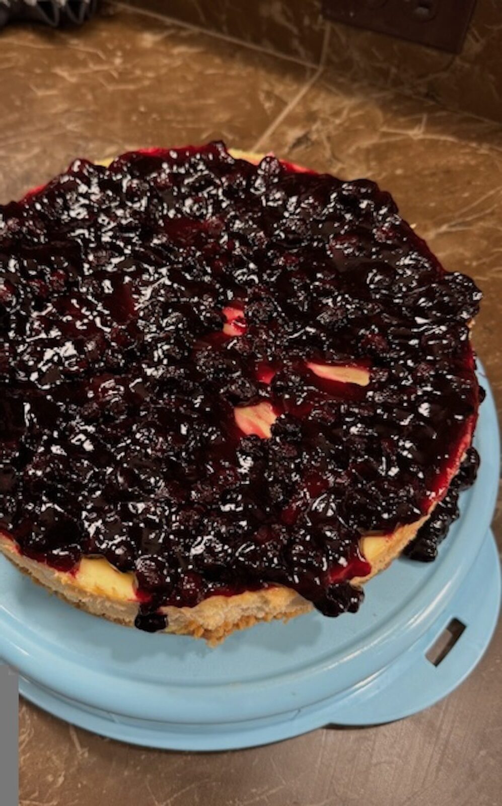 Lemon blueberry cheesecake on a blue cake stand.