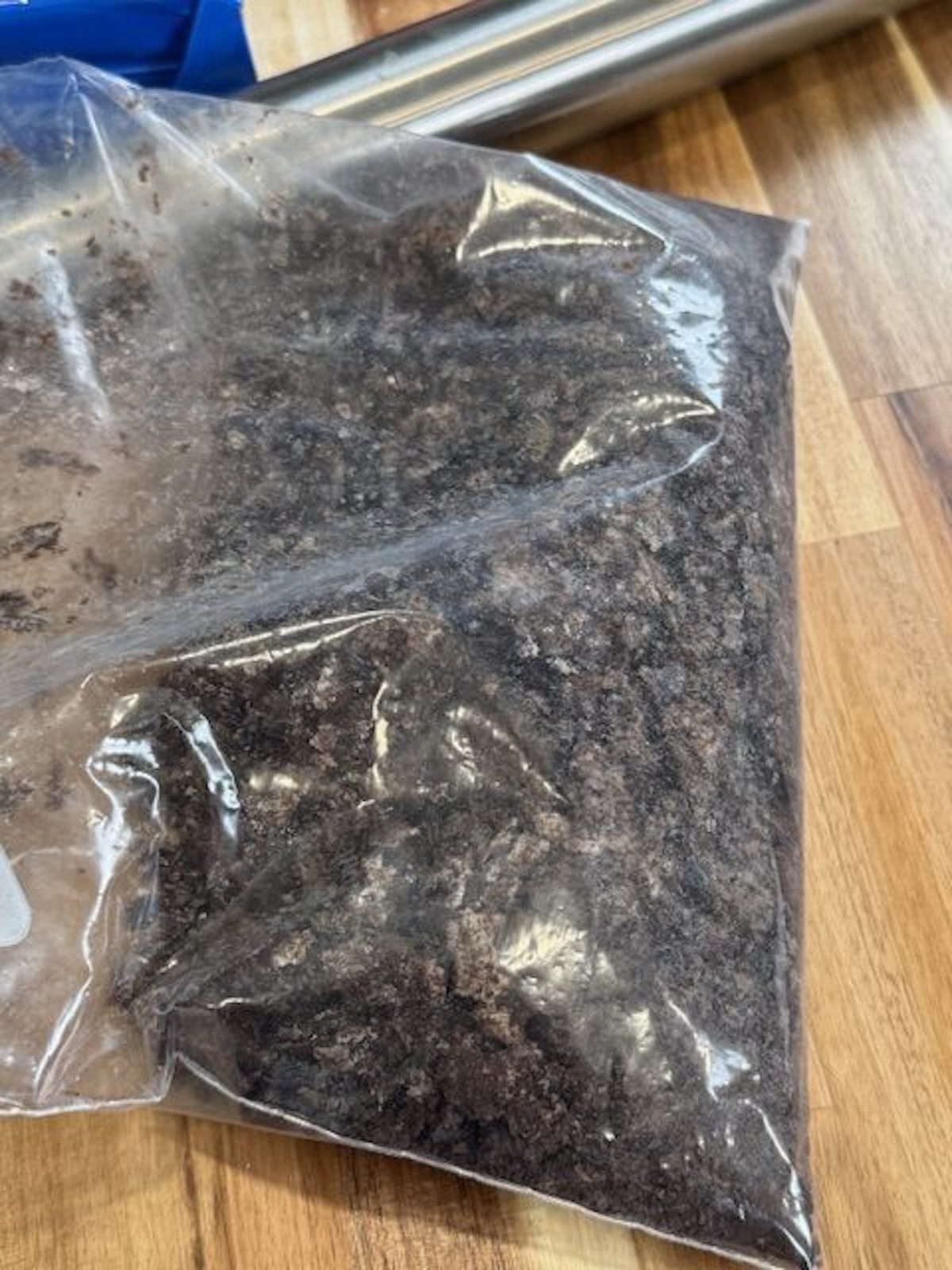 Crushed Oreos in a plastic bag with metal rolling pin on the side.