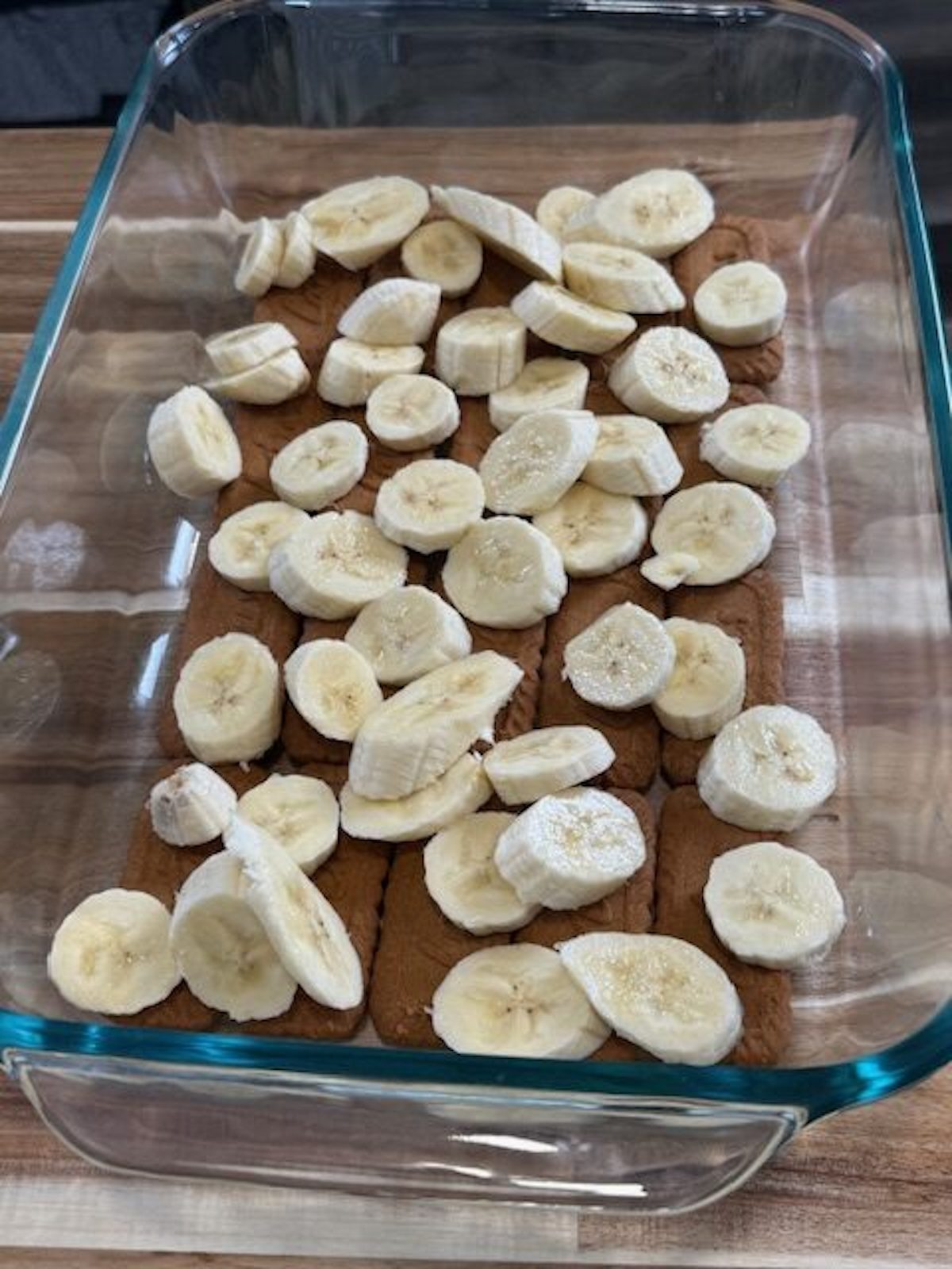 Sliced bananas are layered over Biscoff cookies.