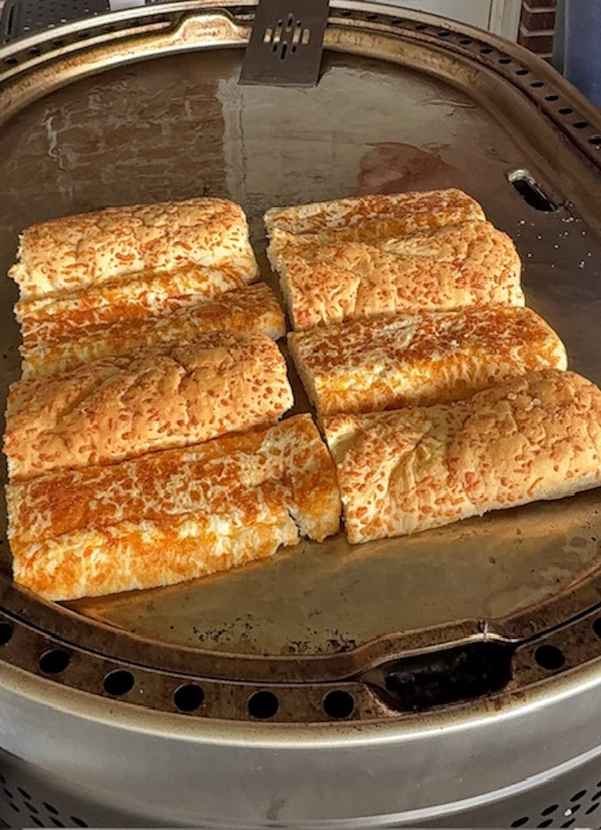 Sub bread toasting on the griddle for cheesesteaks.
