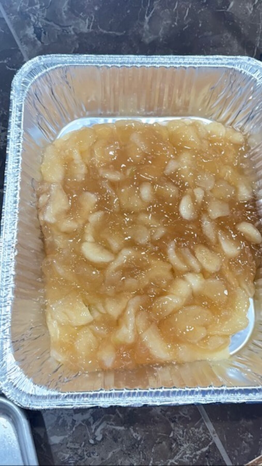 Apple pie filling in a metal casserole container.