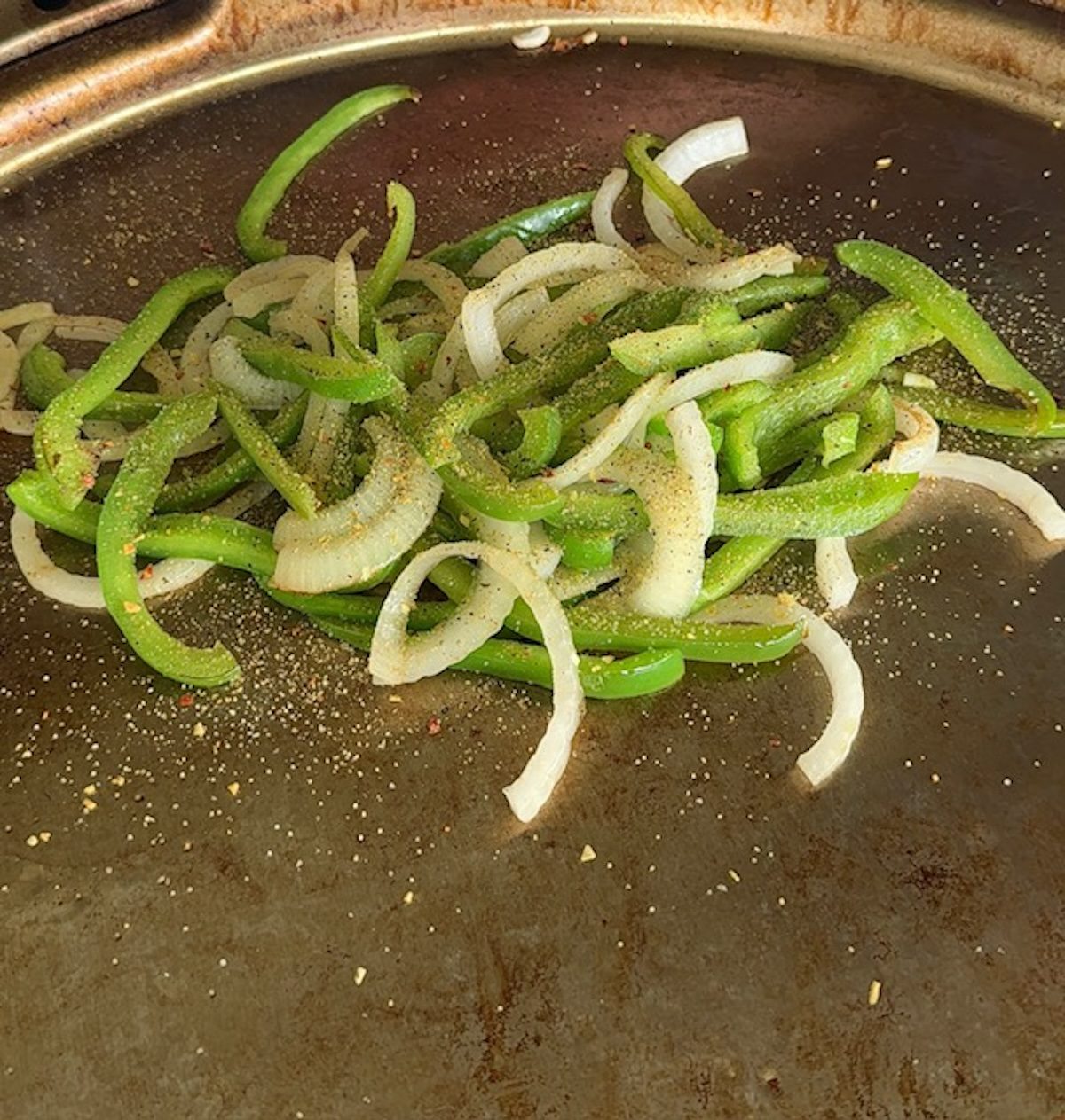 Peppers and onions on the griddle for cheesesteaks.