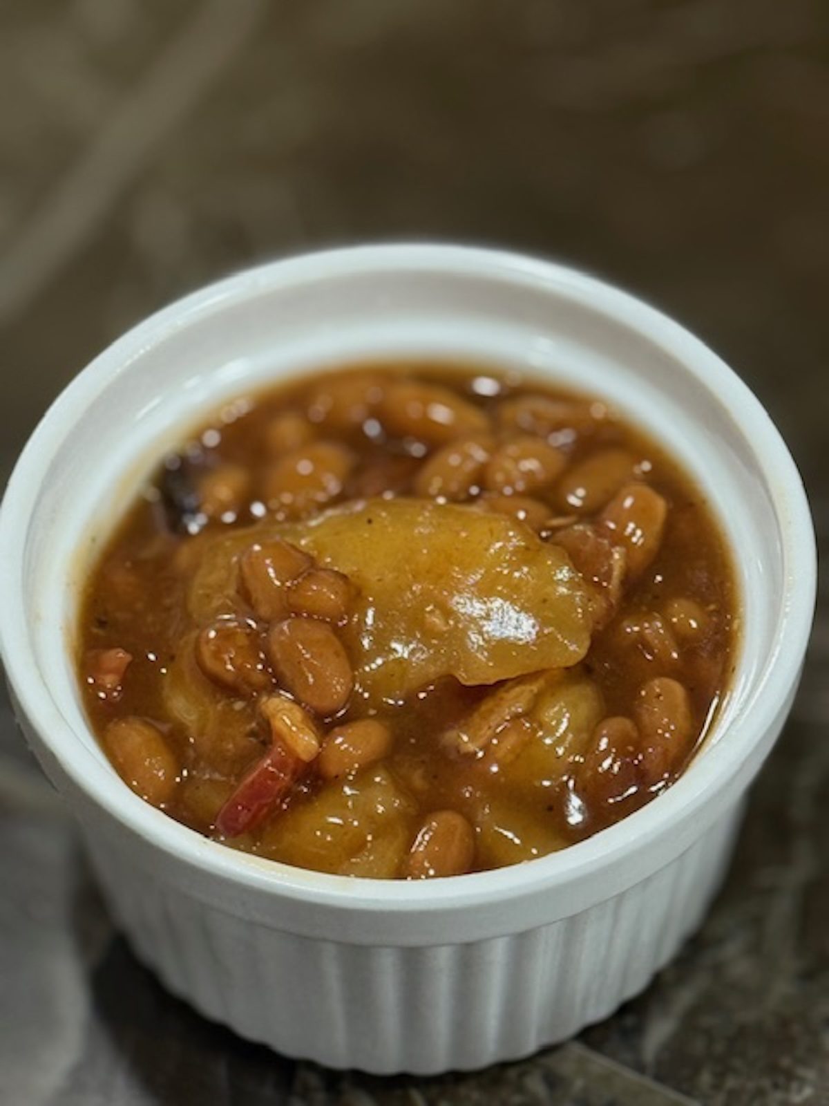 Apple pie baked beans in a white ramekin.