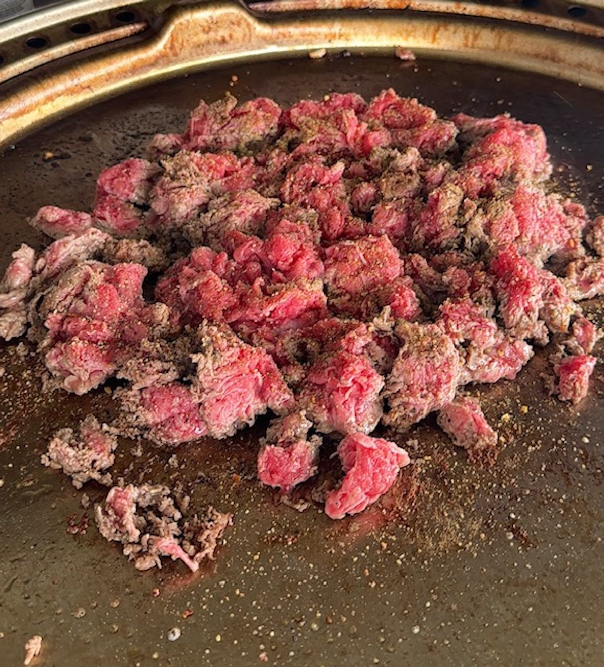 Shaved beef on the griddle with spices for philly cheesesteaks.