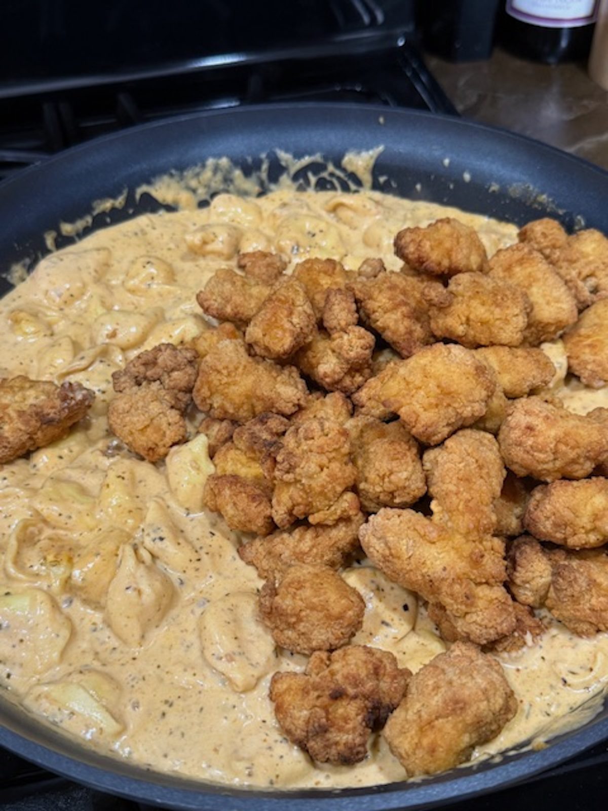 Chicken tenders being added to the marry me chicken pasta sauce.