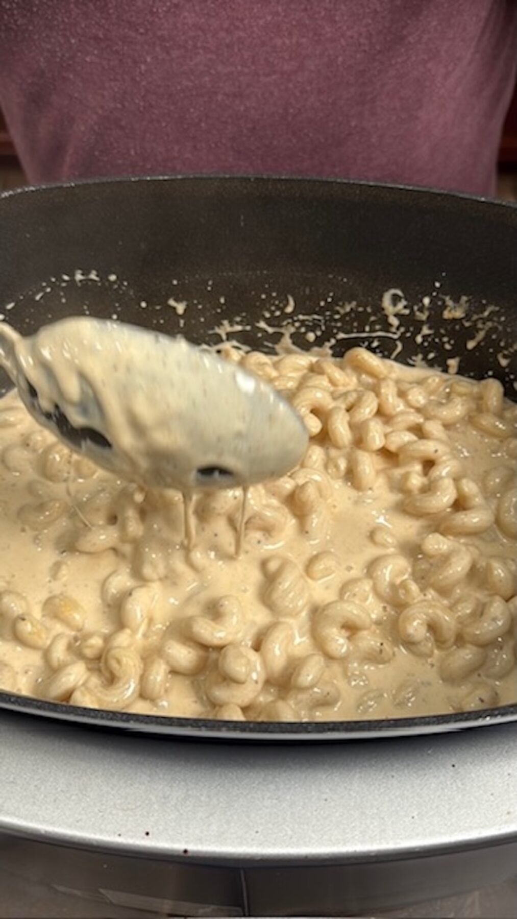 A spoon scooping out mac and cheese from the slow cooker.