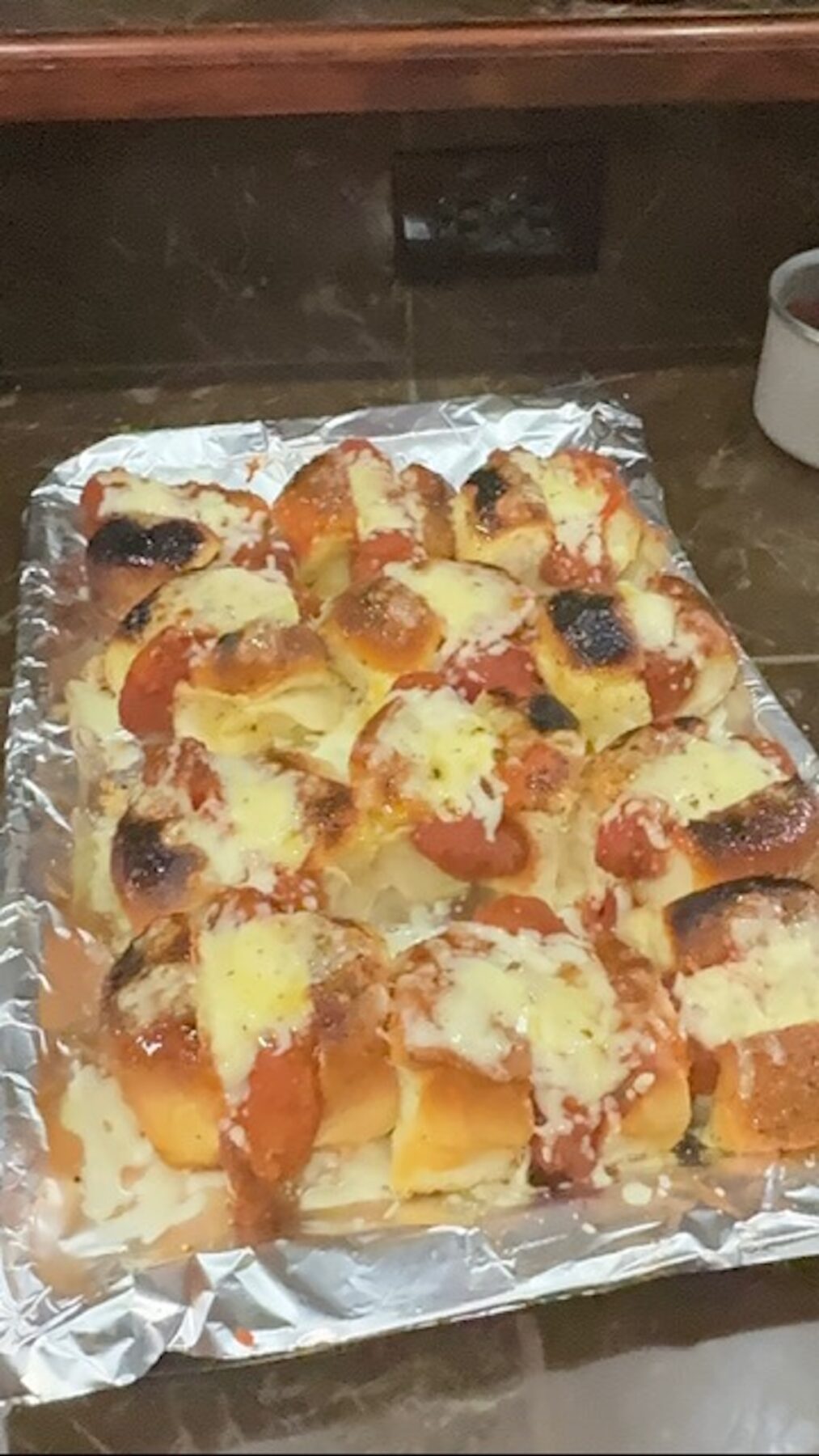 Baked chicken parm sliders on a foil-lined baking sheet.