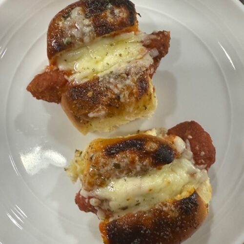 Chicken parm sliders baked on a white plate.