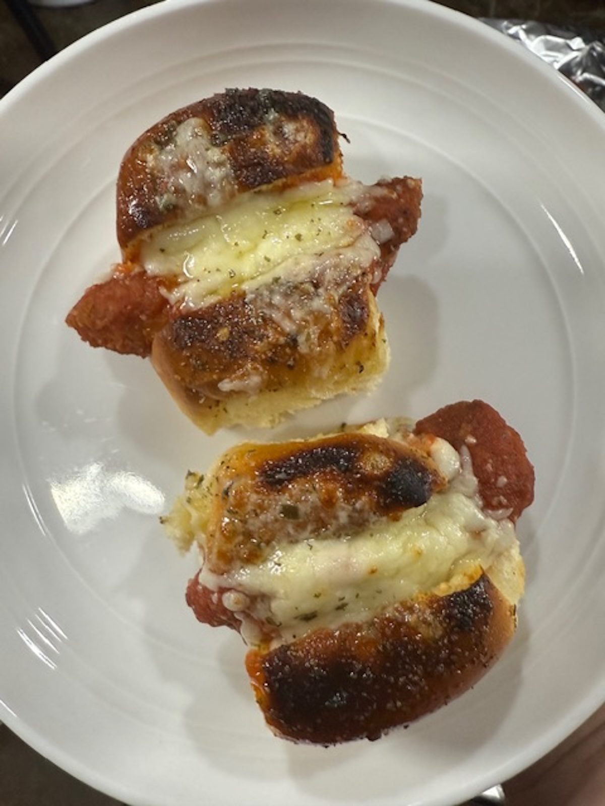 Chicken parm sliders baked on a white plate.