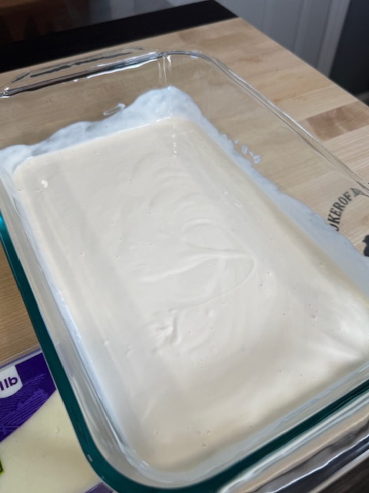 Cream and alfredo sauce are added to a glass casserole dish.