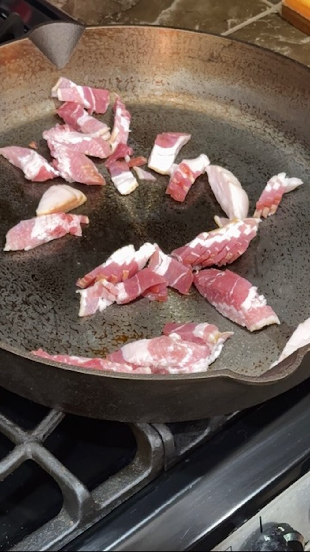 Bacon cooking in a skillet.