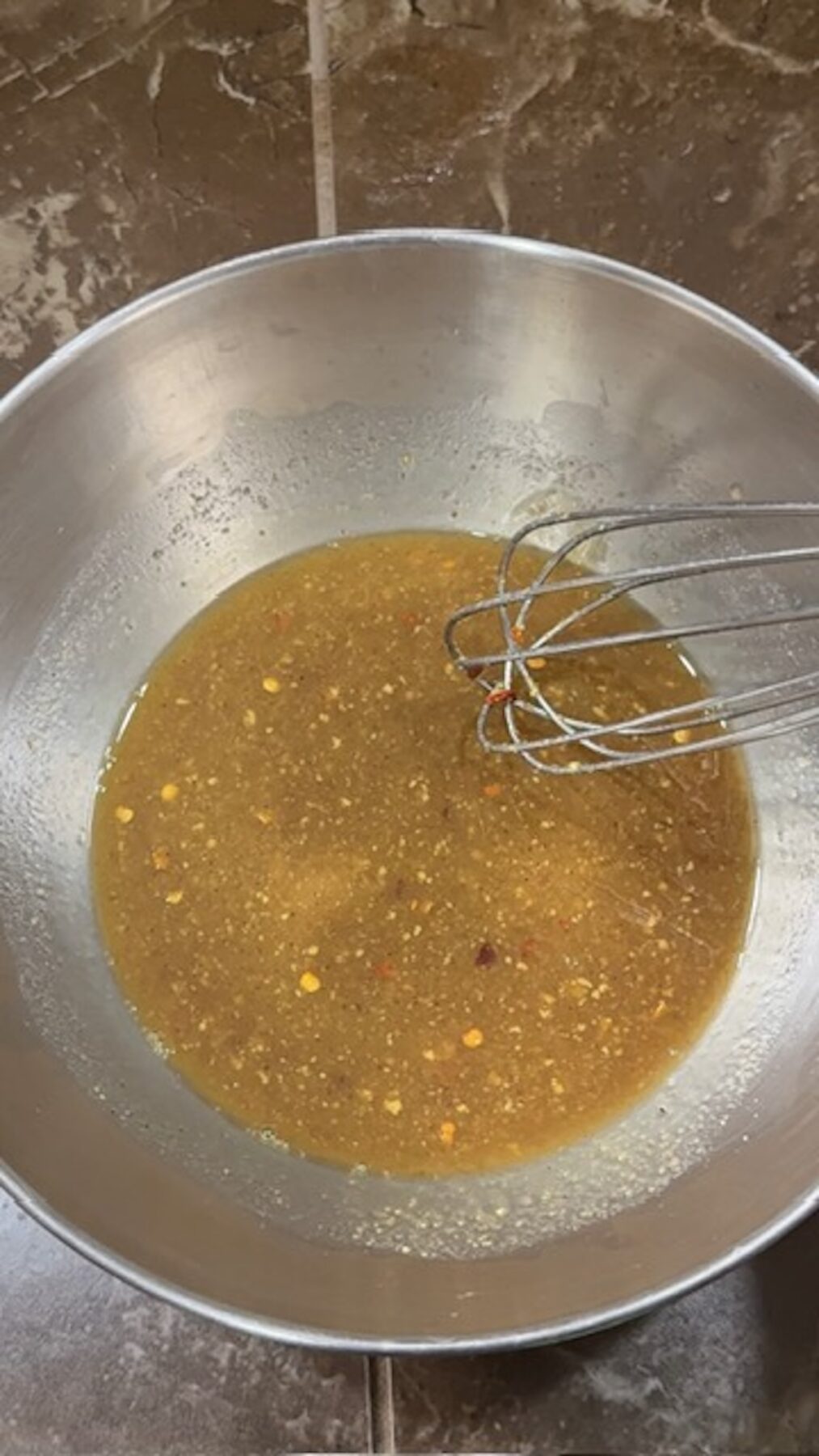 Green beans with bacon sauce mixed in a bowl with a whisk.