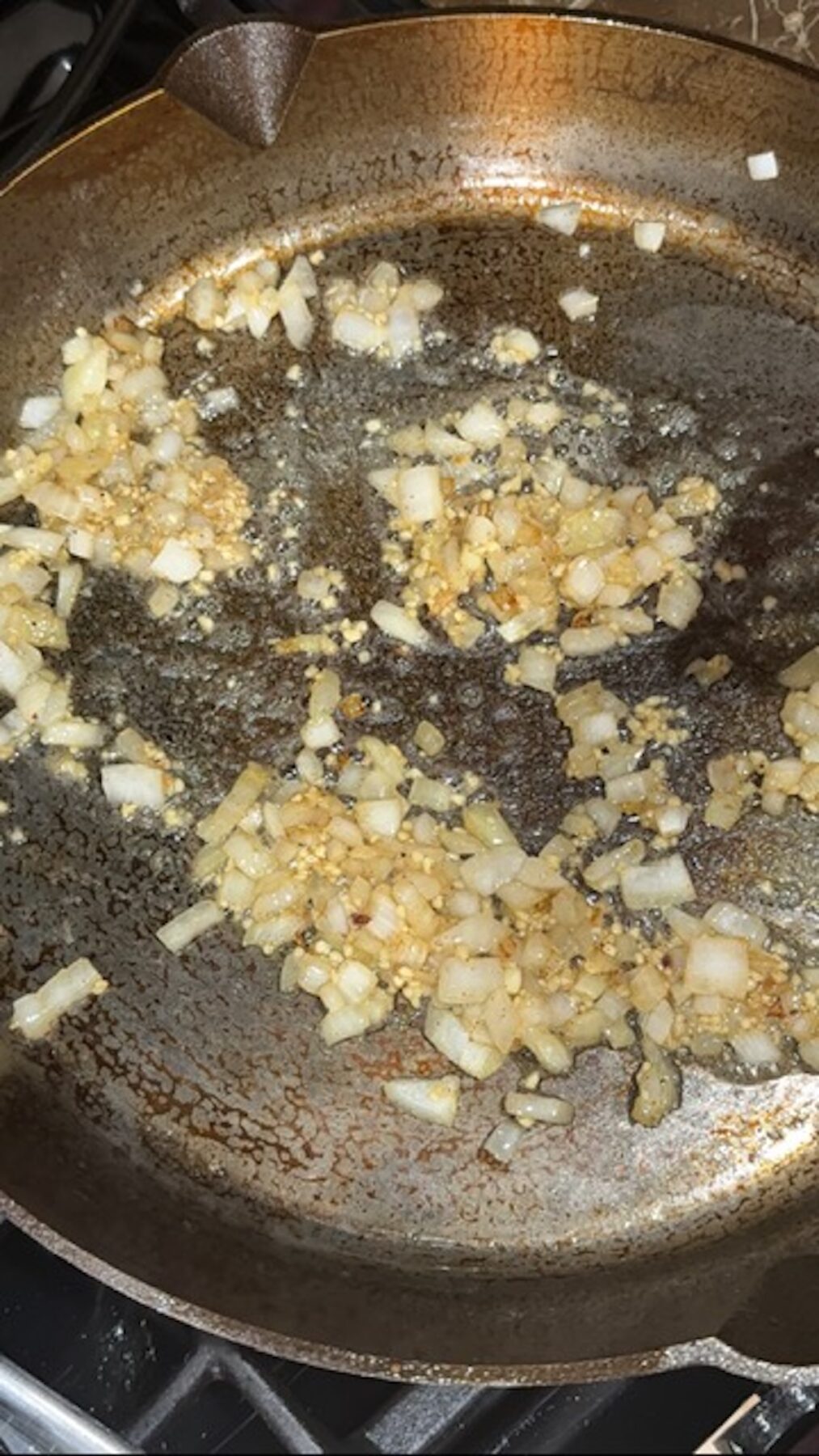 Onions cooking in bacon fat in a skillet.