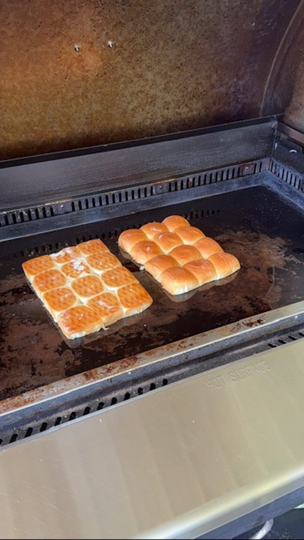 Toasted slider buns on a griddle cooktop.