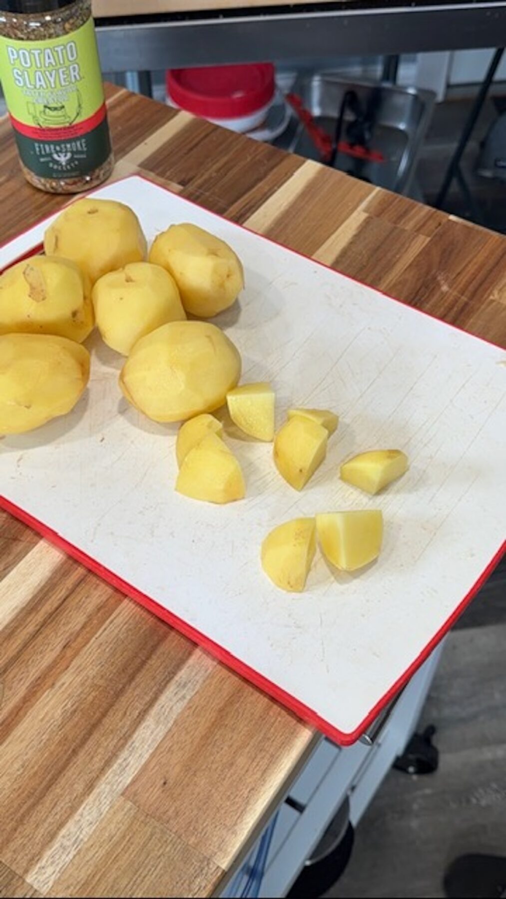 Peeled potatoes being cut into cubes on a cutting board.