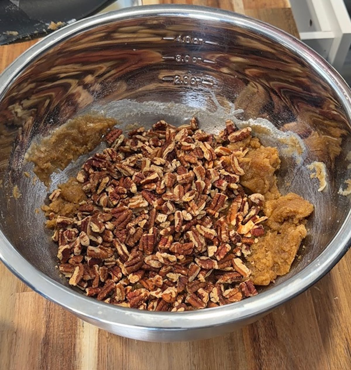 A metal bowl with pecans, brown sugar, butter, and flour.