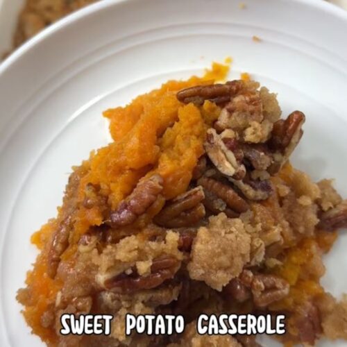 A serving of sweet potato casserole with pecan topping on a white plate.
