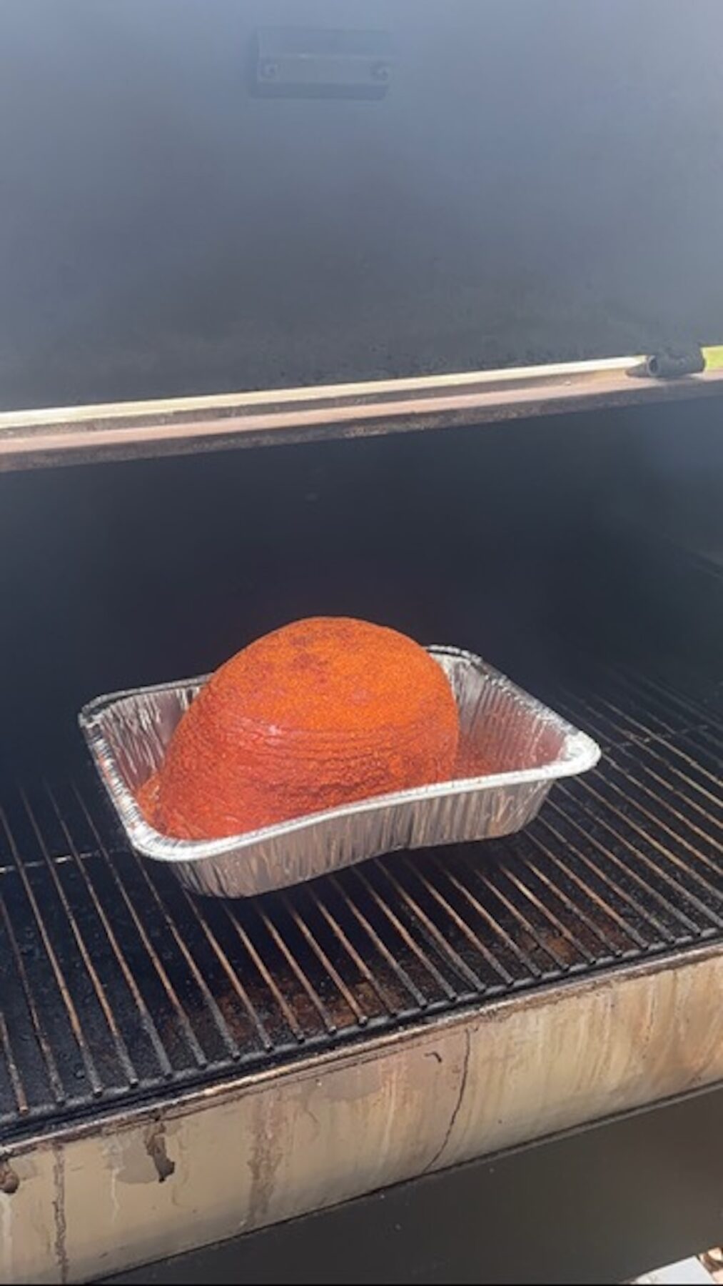 Ham in foil tin on a smoker.