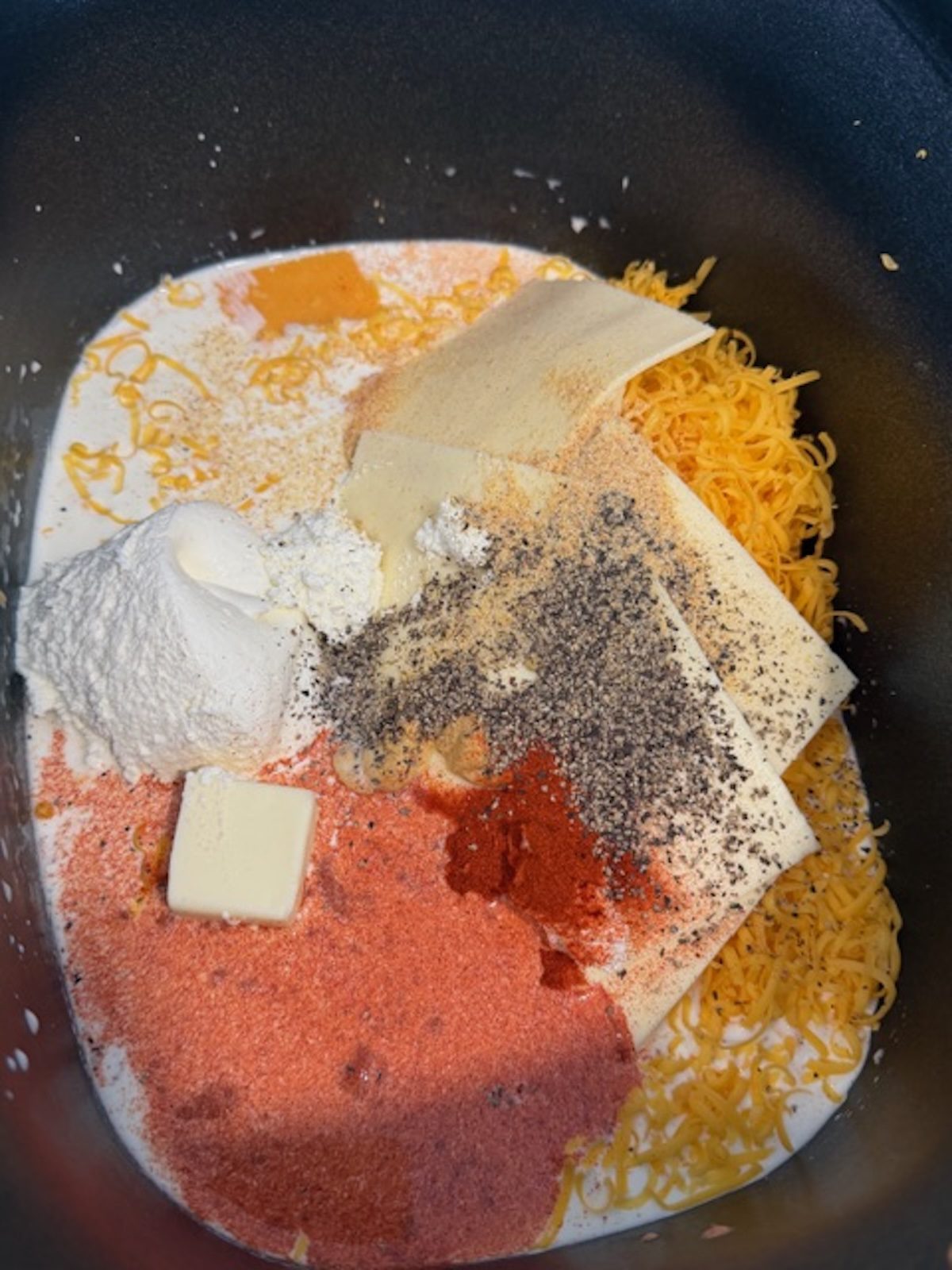 Ingredients in a slow cooker bowl for tortellini and cheese.