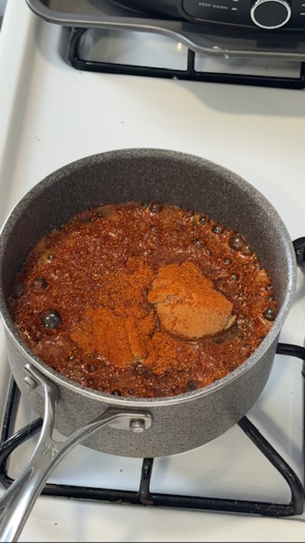 Glaze for coca cola ham in a saucepan simmering on the stove.