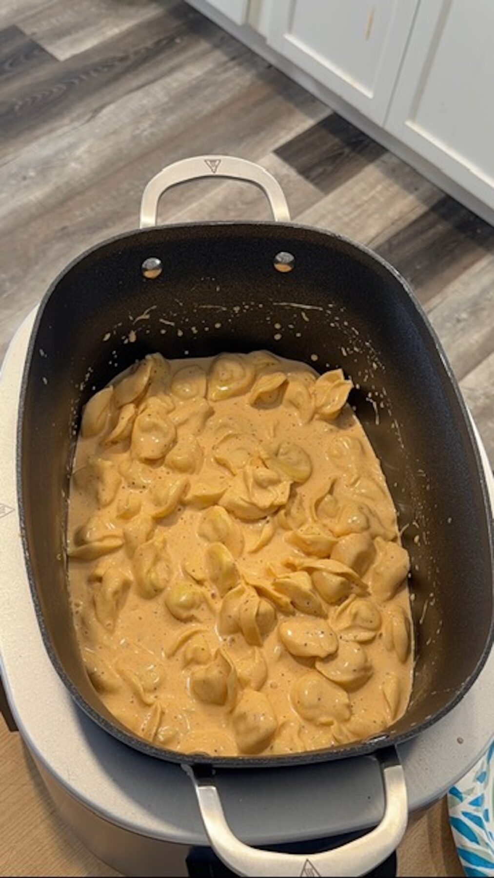 Slow cooker tortellini and cheese in a black crockpot bowl.