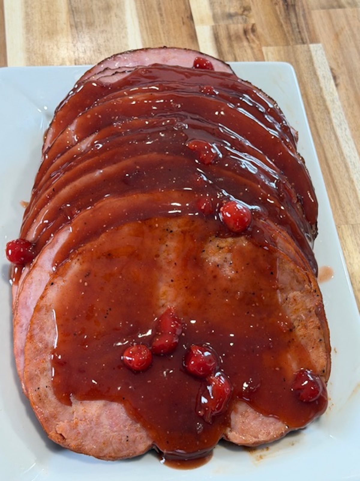 Sliced coca cola ham on a white platter.