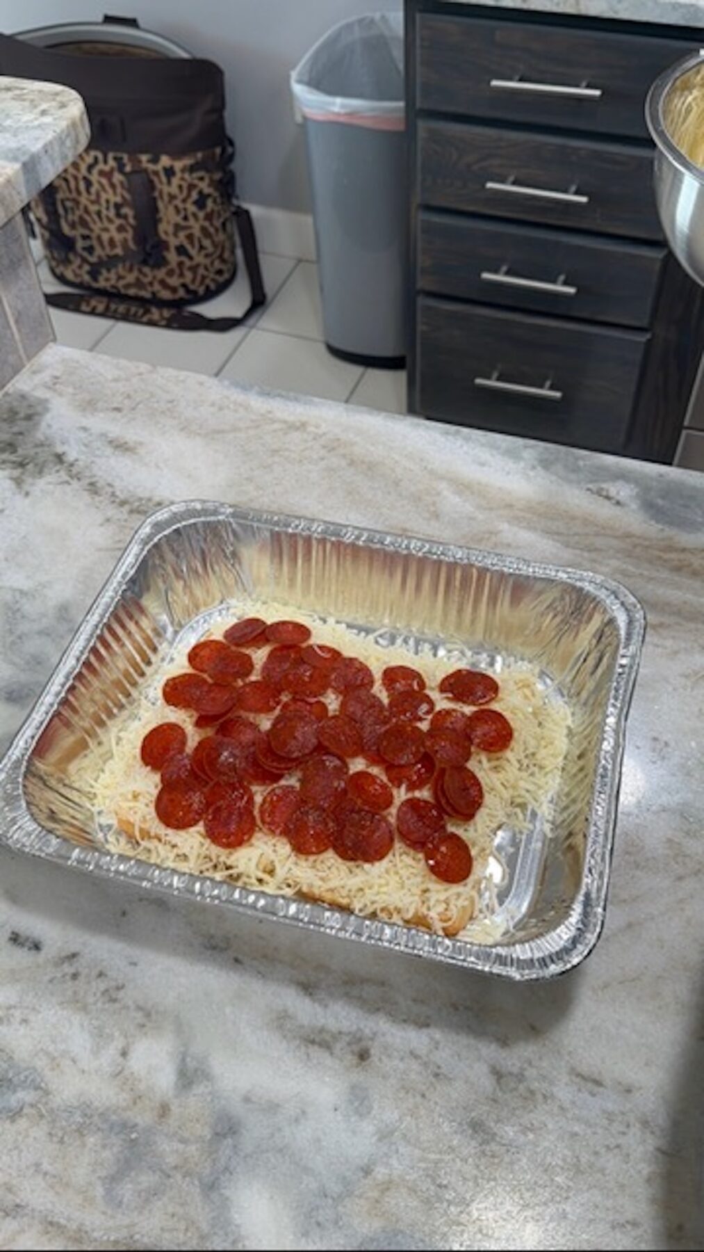 A foil tray with Hawaiian buns, shredded cheese, and pepperoni.